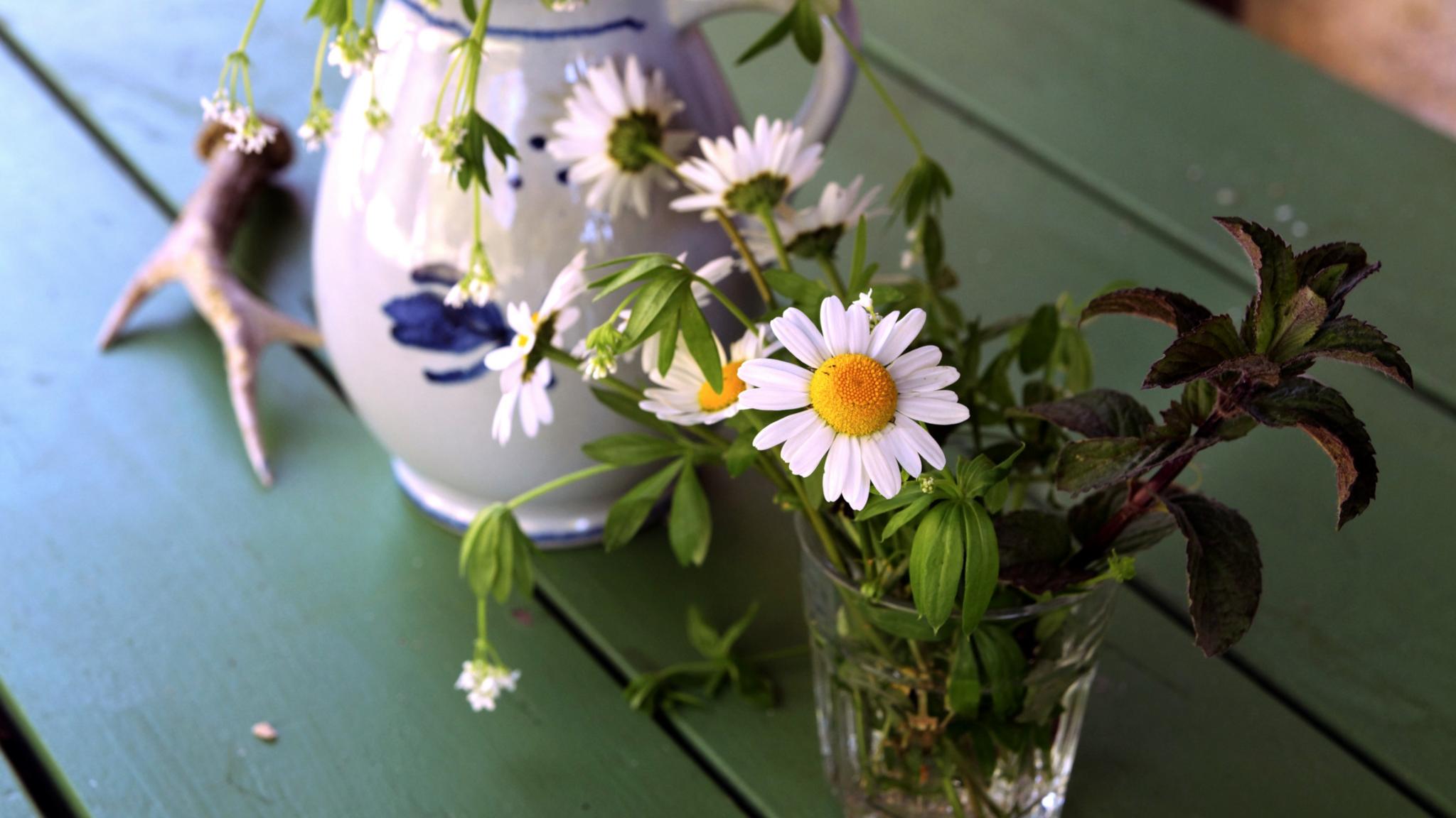 Ein Tisch mit Glas und Krug und Gartenblumen