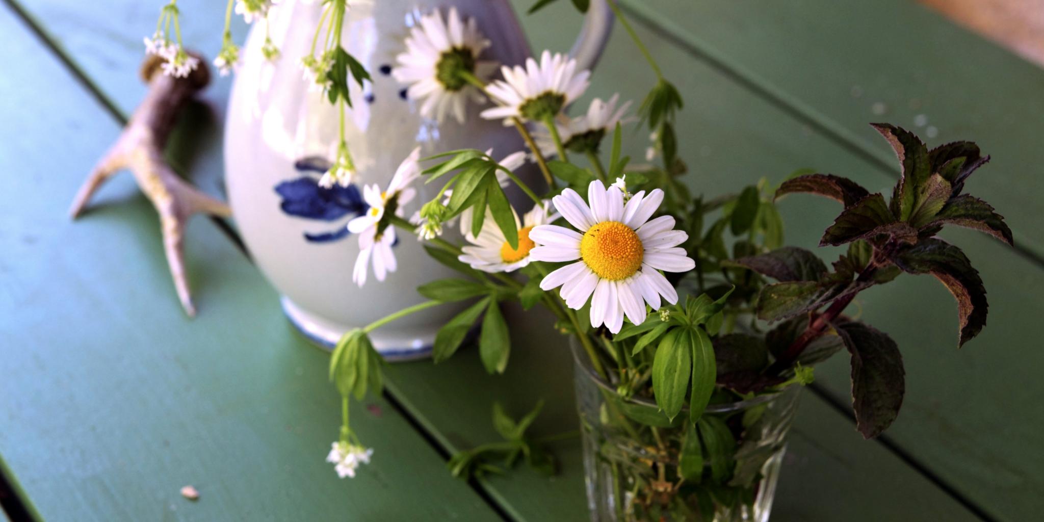 Ein Tisch mit Glas und Krug und Gartenblumen
