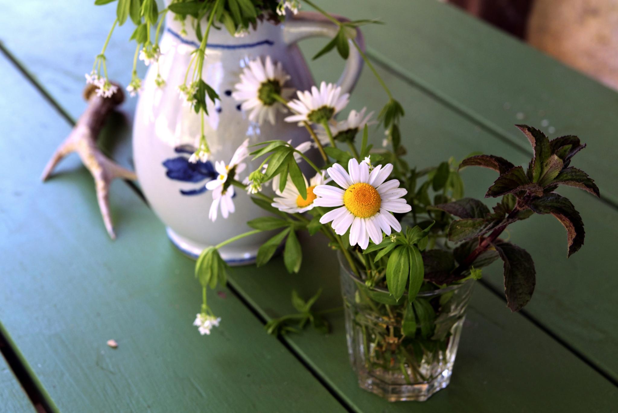 Ein Tisch mit Glas und Krug und Gartenblumen