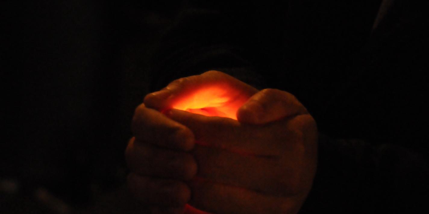 In der Dunkelheit ein Licht von Händen gehalten