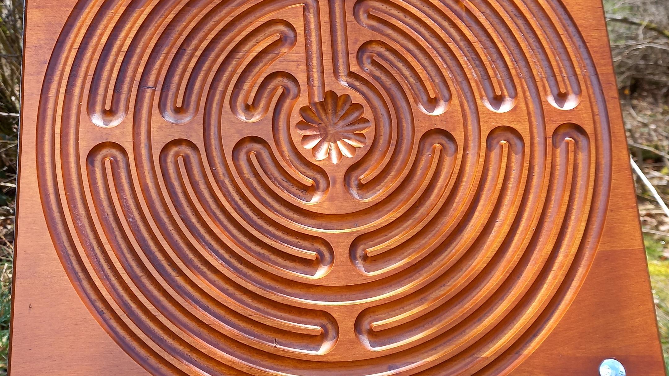 Im Wald hängt eine Holzscheibe mit einem Labyrinth