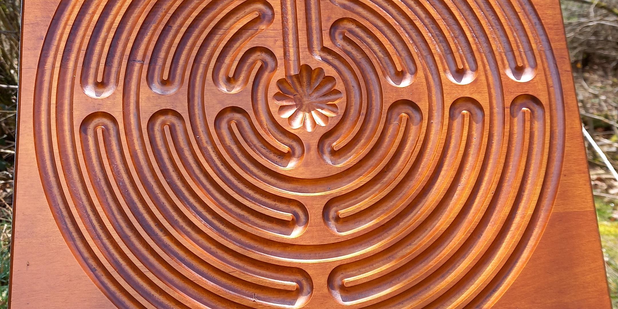 Im Wald hängt eine Holzscheibe mit einem Labyrinth