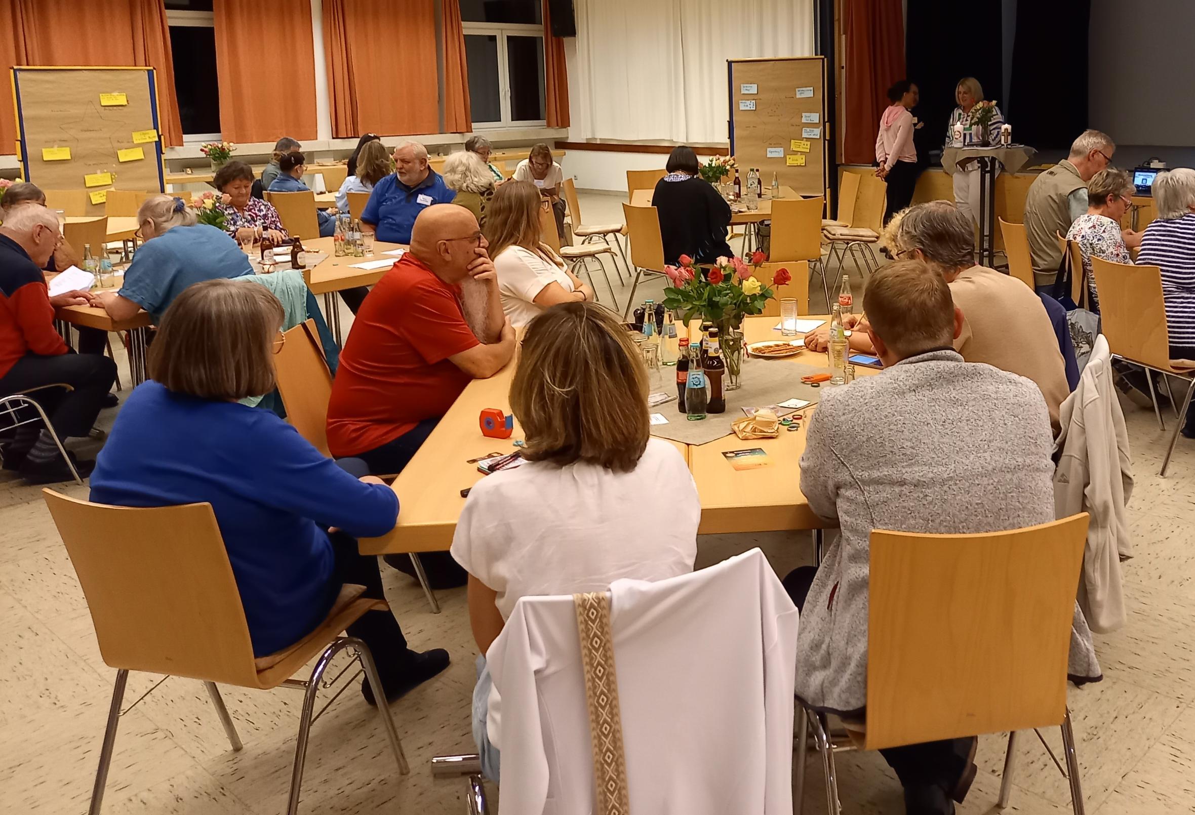 Menschen sitzen an Tischen und hören zu