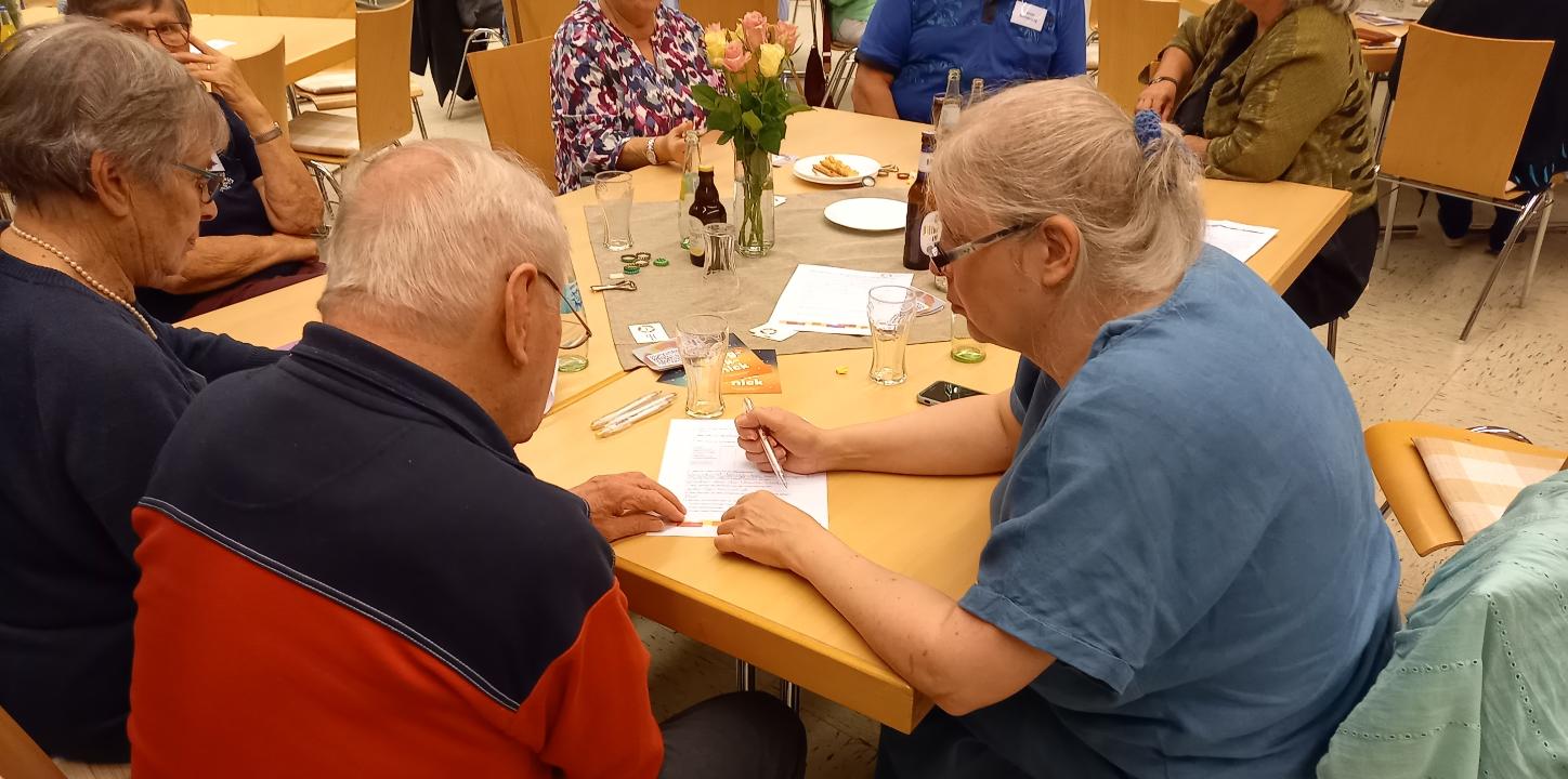 Zwei  Menschen am Tisch über einen Zettel gebeugt