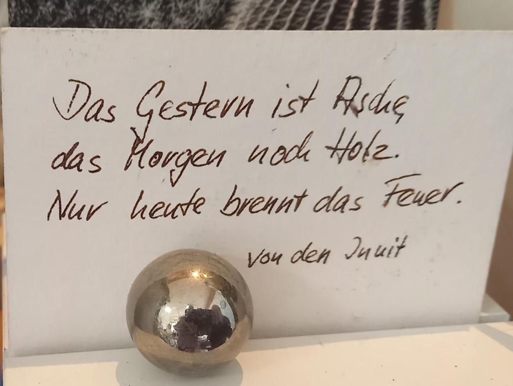 Auf einem Zettel steht ' Das Gestern ist Asche, das Morgen noch Holz. Nur heute brennt das Feuer'