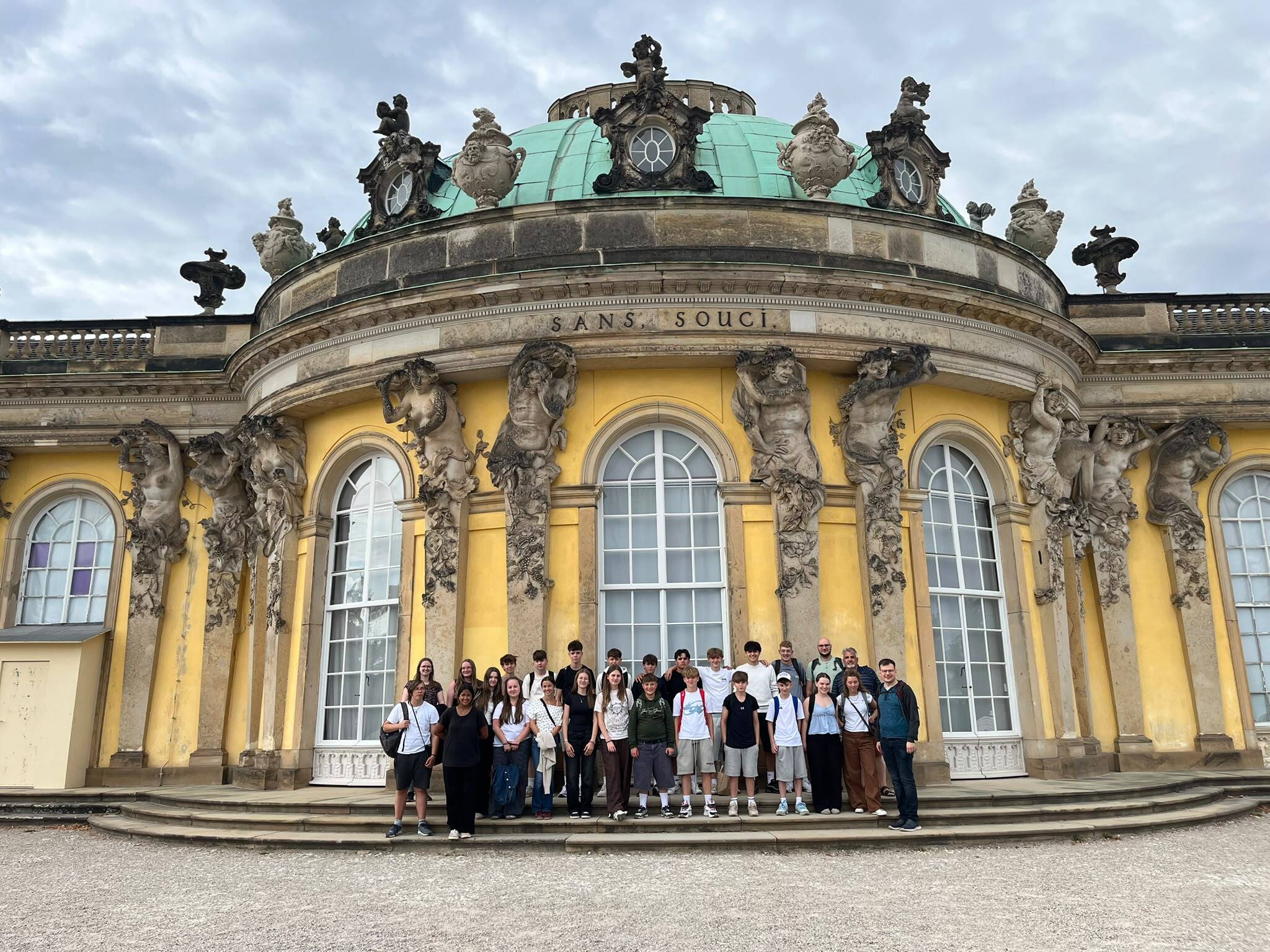 Jugendliche sitzen als Gruppe vor einem Schloss in Berlin