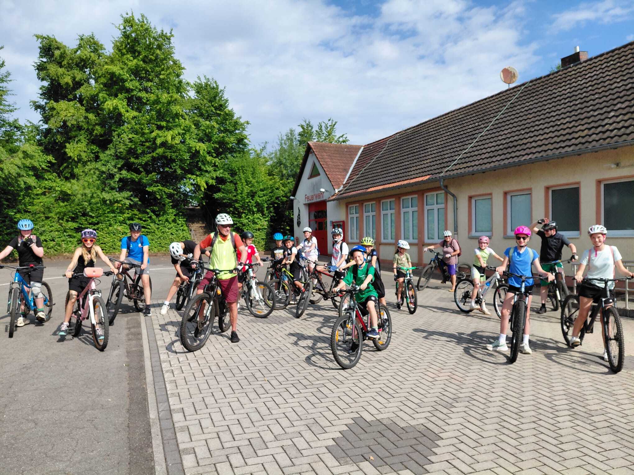 Kinder und Jugendliche sitzen auf Fahrrädern vor einem Haus