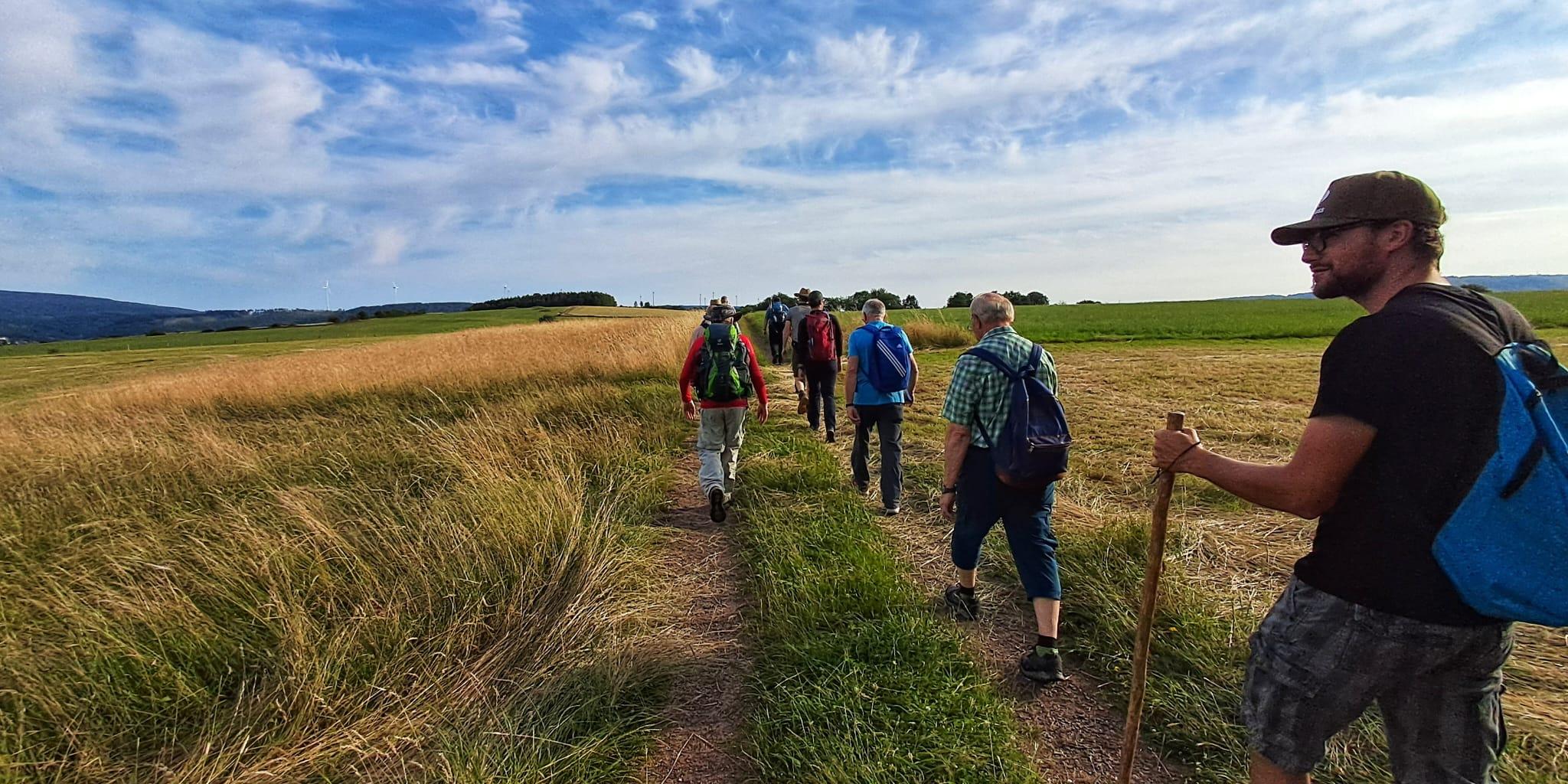 Männer wandern über eine grüne Wiese