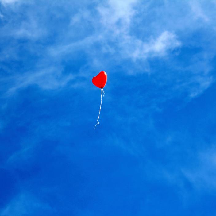 Ein einzelner roter Luftballon am Himmel