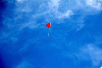 Ein einzelner roter Luftballon am Himmel