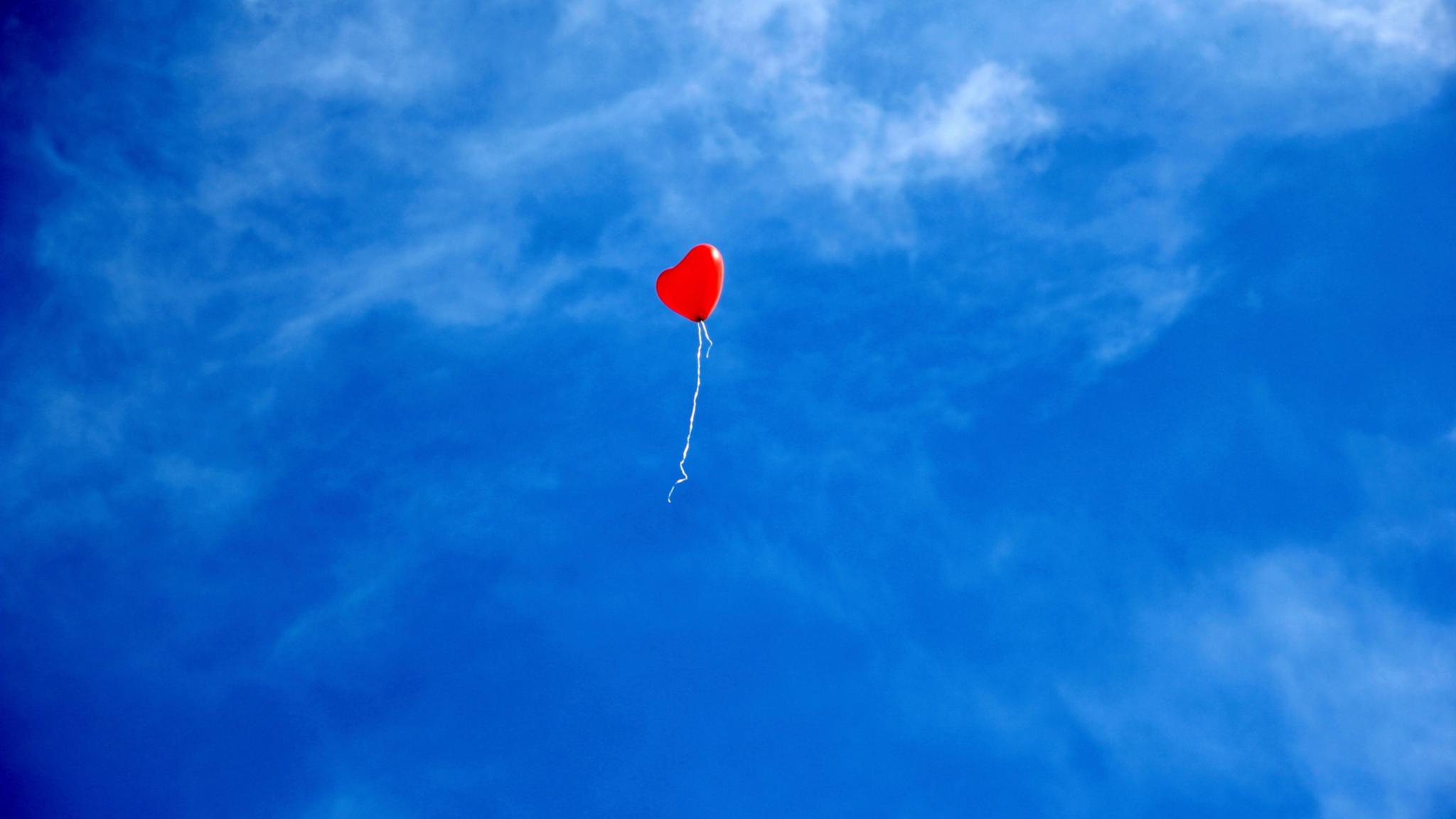 Ein einzelner roter Luftballon am Himmel