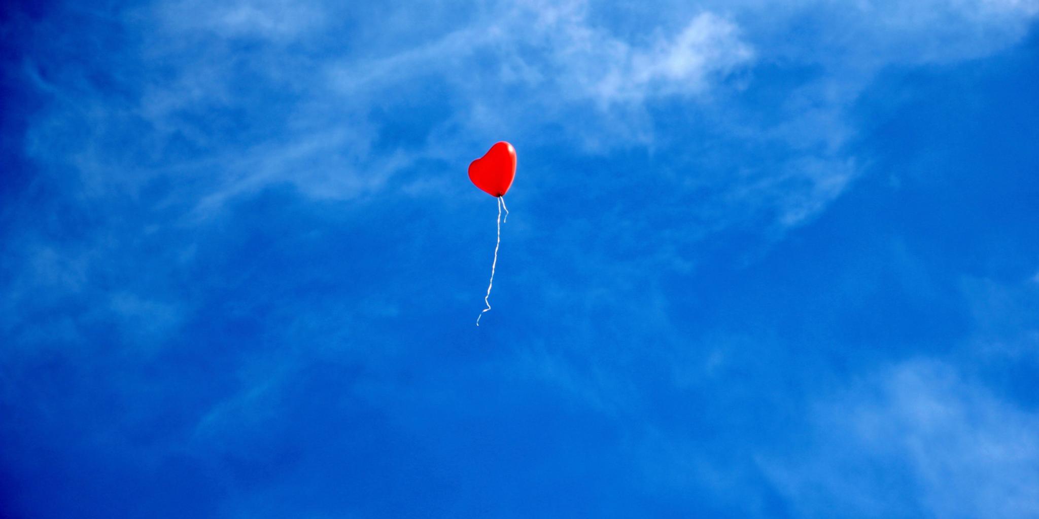 Ein einzelner roter Luftballon am Himmel