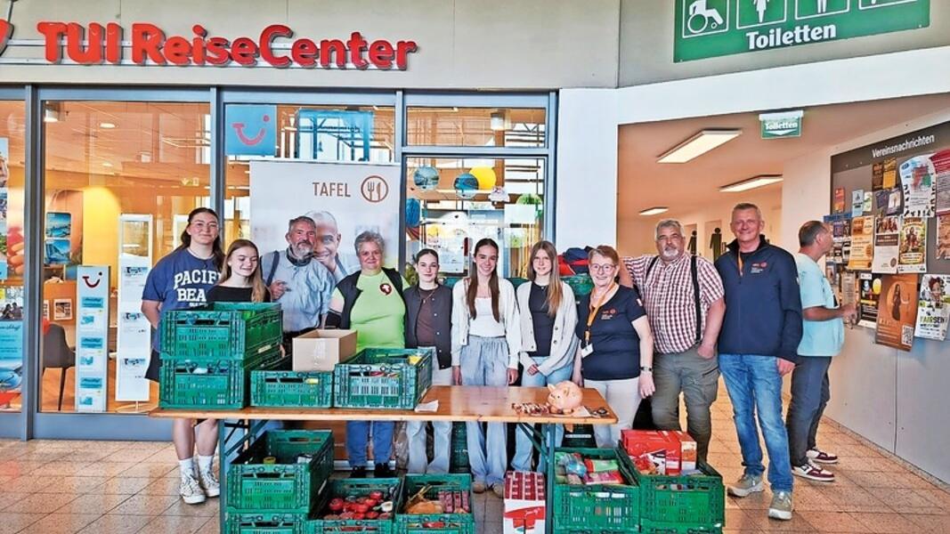 Eine Gruppe von Menschen im Globus Losheim hinter einem Tisch mit gesammelten Gaben für die Tafel Wadern