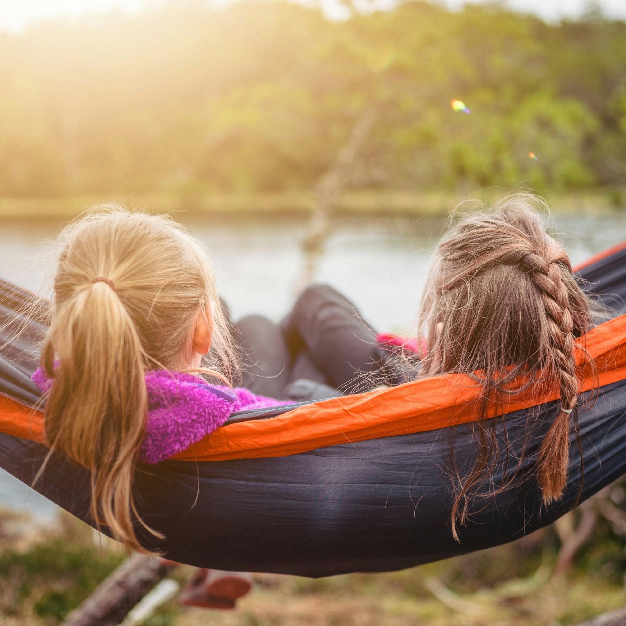 Zwei Mädchen sitzen nebeneinander in der Hängematte