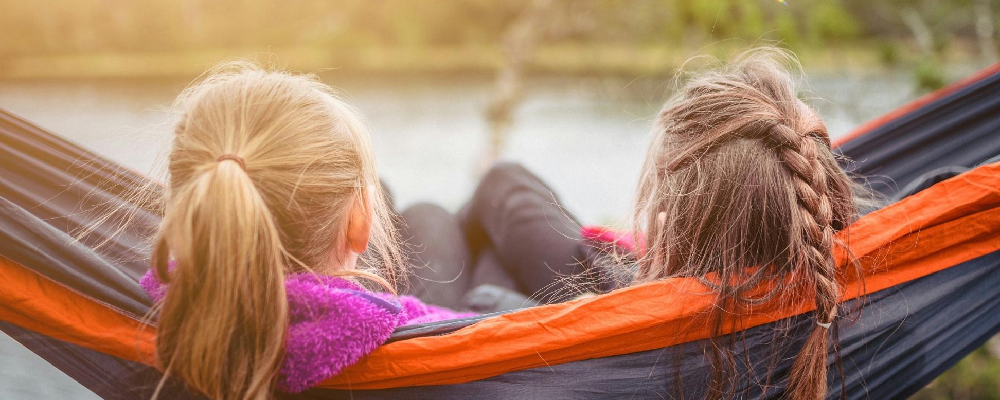 Zwei Mädchen sitzen nebeneinander in der Hängematte