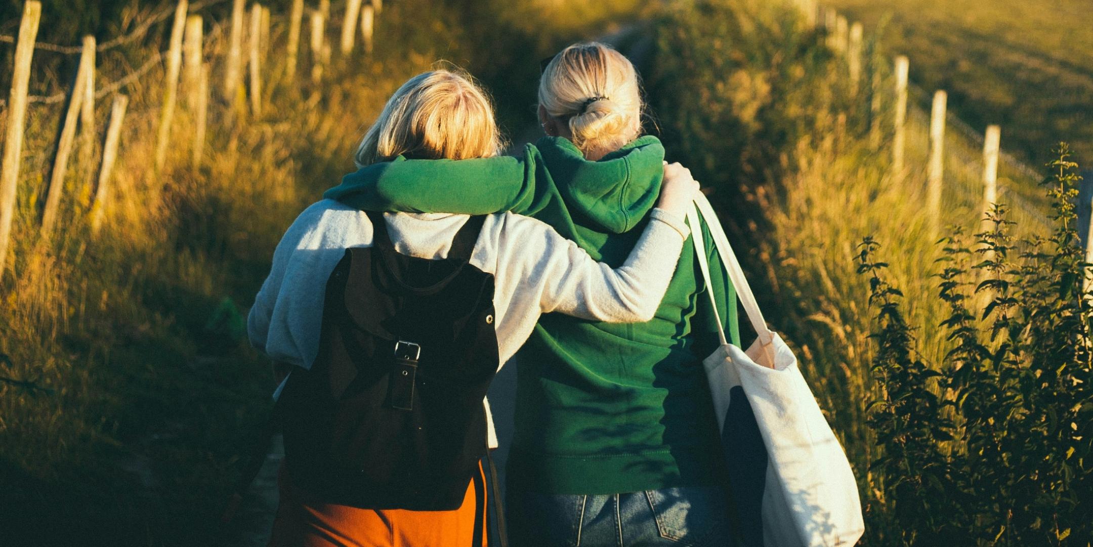 Zwei Freunde gehen umarmt einen Weg