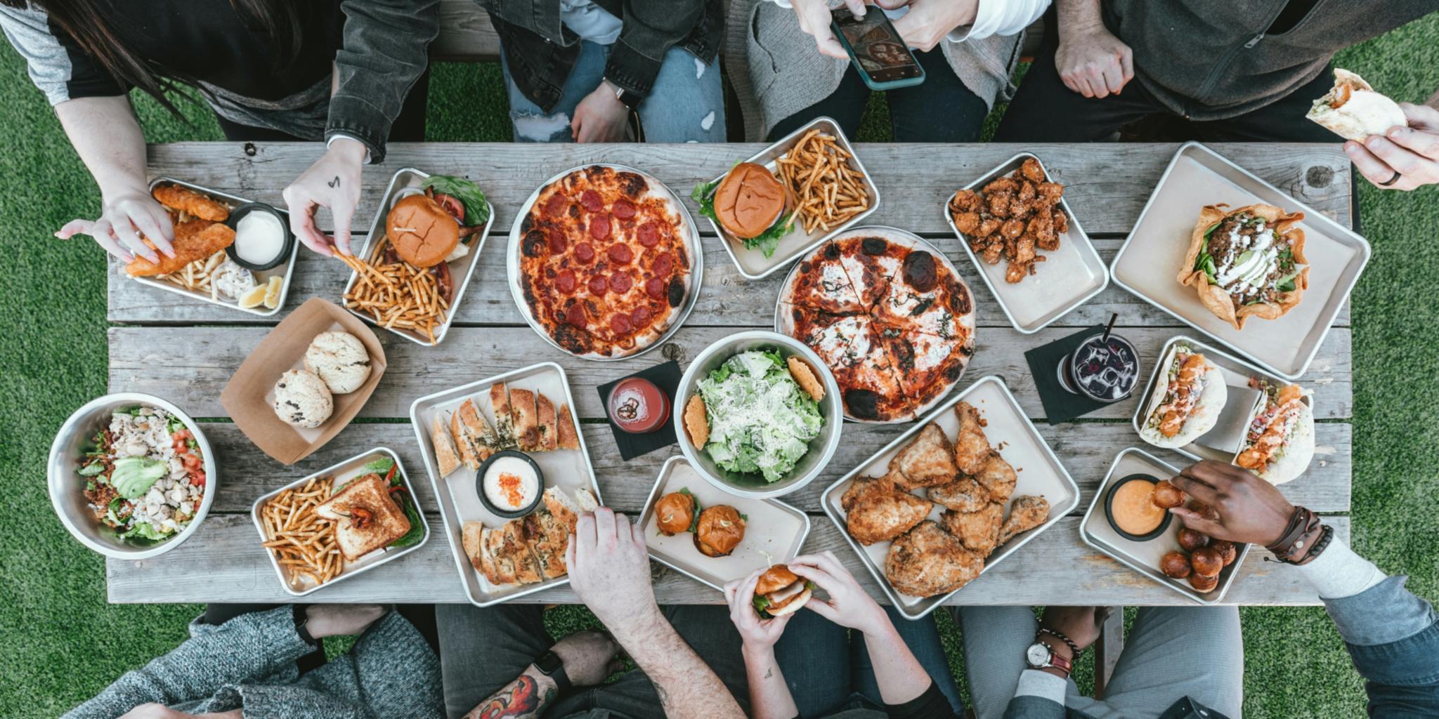 Mehrere Personen sitzen zusammen an einem Tisch und essen, von oben fotografiert